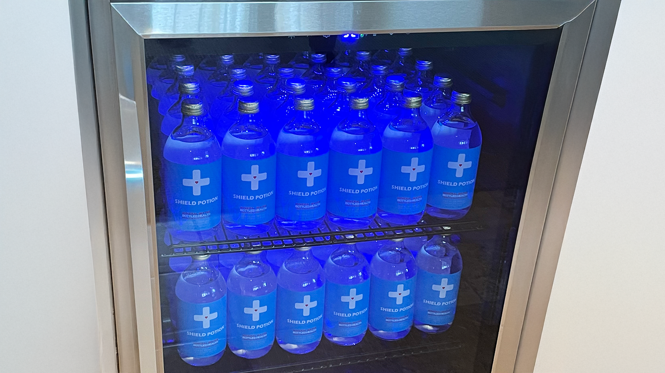 Mineral water stacked in fridge and blue light on the bottles making them glow blue.